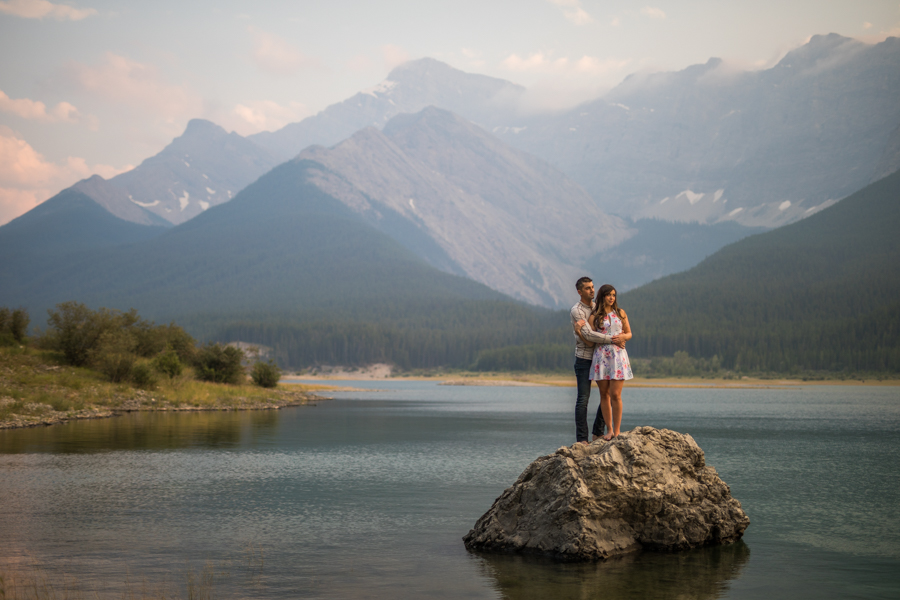 couple standing on a rock, canmore engagement session, engagement session in the water