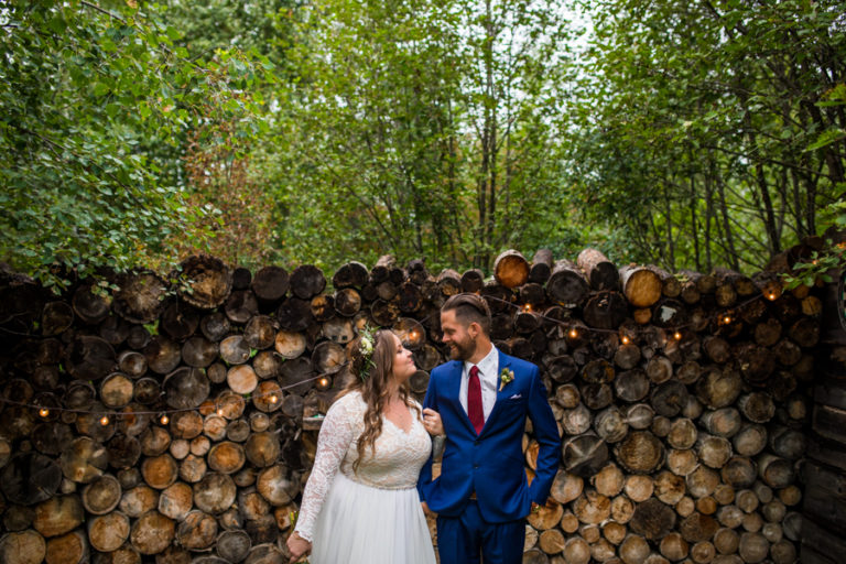 woodland and wildflower wedding venue with the bride and groom in front of the wood pile