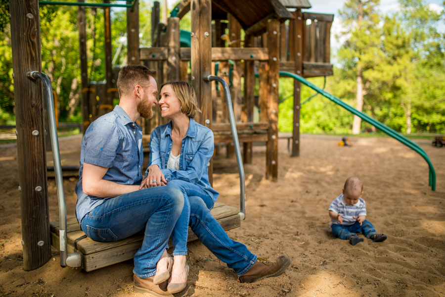 mom and dad kissing while baby plays