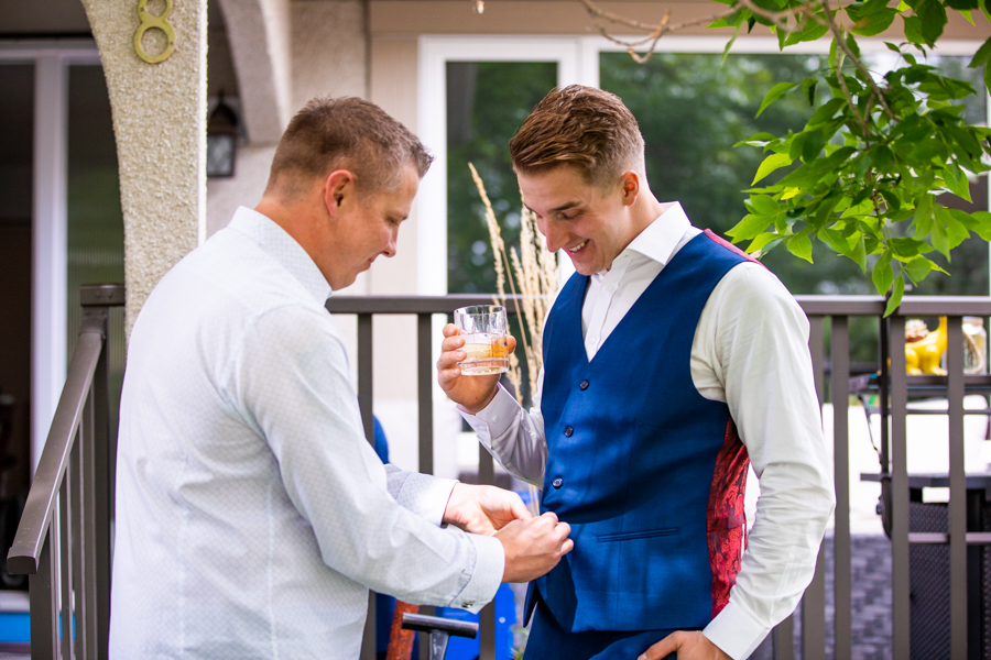 groom getting his vest buttoned up