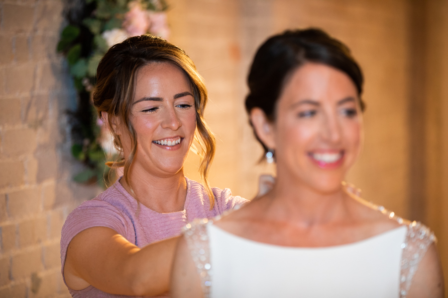 sister helping bride with dress in rooftop wedding in edmonton