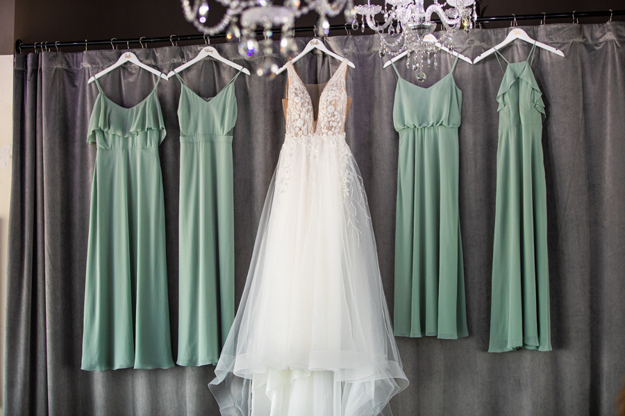 brides maids drees and bridal gown hanging in make up shop