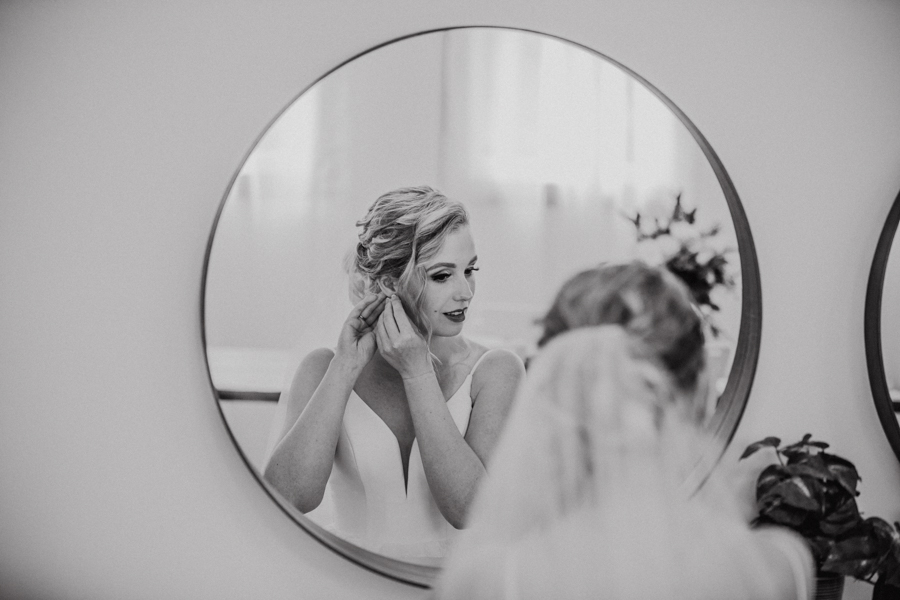 bride in mirror getting ready at the school house on pine and pond wedding venue
