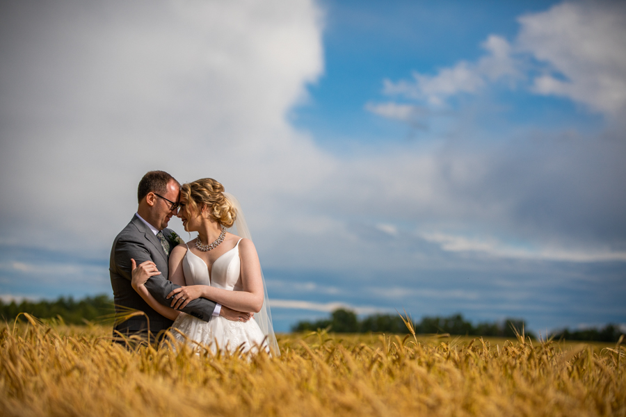 couple standing in a wheat field pine and pond wedding site