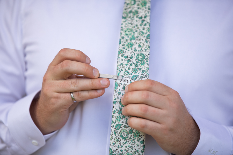 groom putting on tie clip