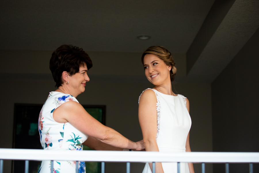mom helping bride wither dress