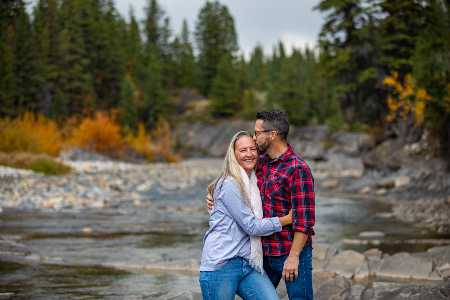 couple kissing along a river bank